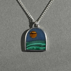 Necklace with a pendant featuring a scenic design on a gray background