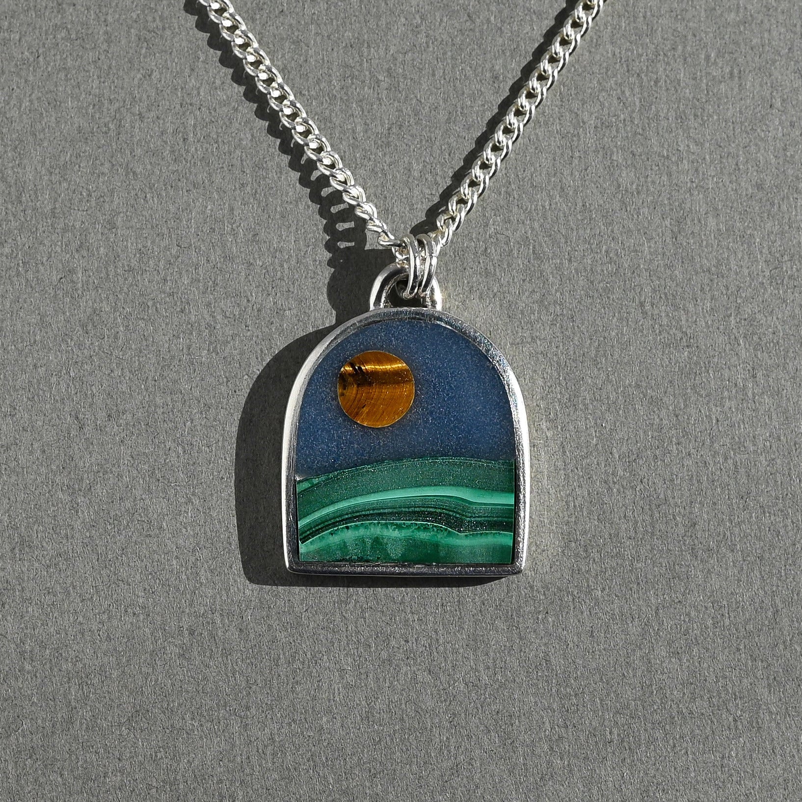 Necklace with a pendant featuring a scenic design on a gray background