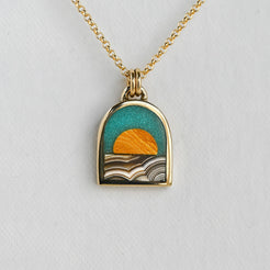 Gold necklace with a pendant featuring a sunset design on a light gray background