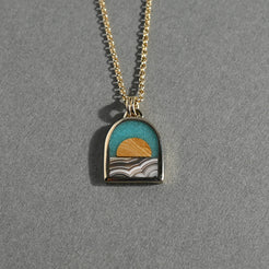 Necklace with a pendant featuring a sunset design on a gray background
