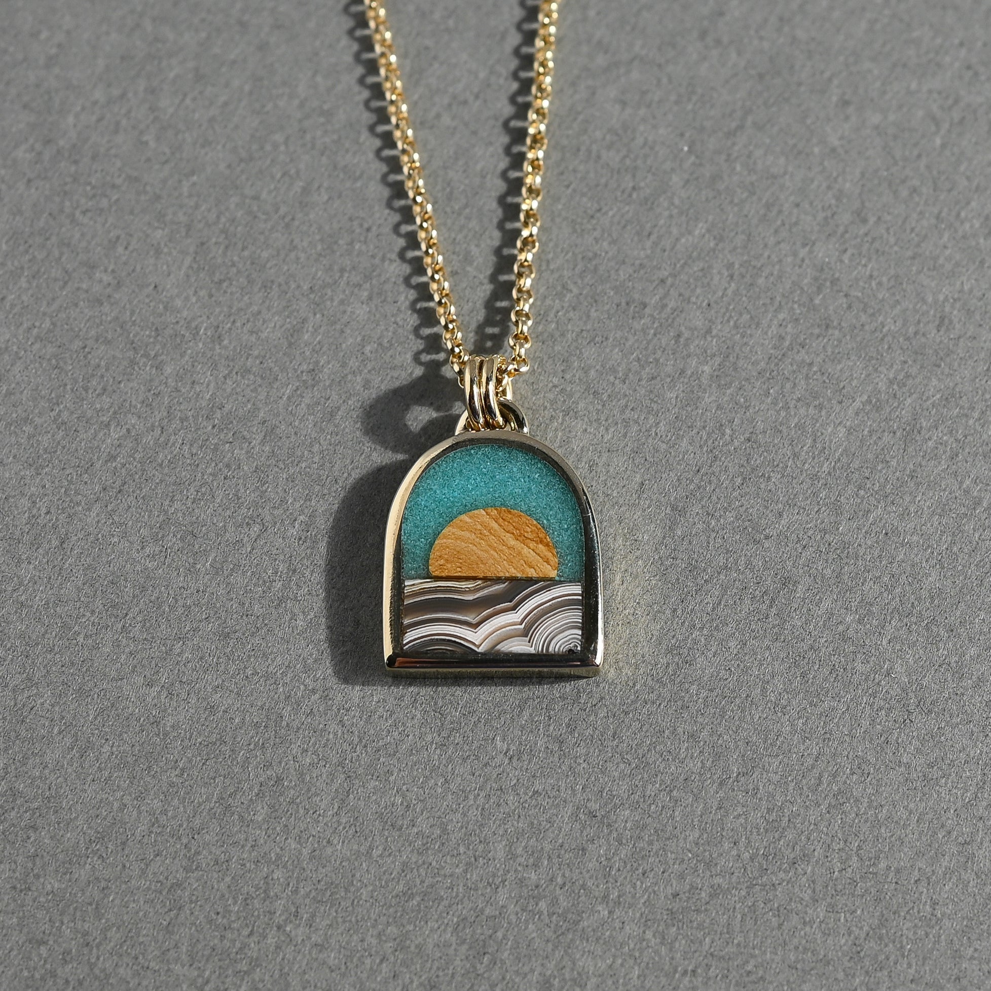 Necklace with a pendant featuring a sunset design on a gray background