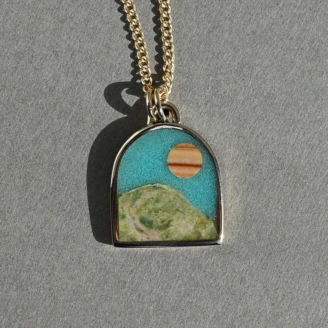 Necklace with a pendant featuring a landscape design on a gray background