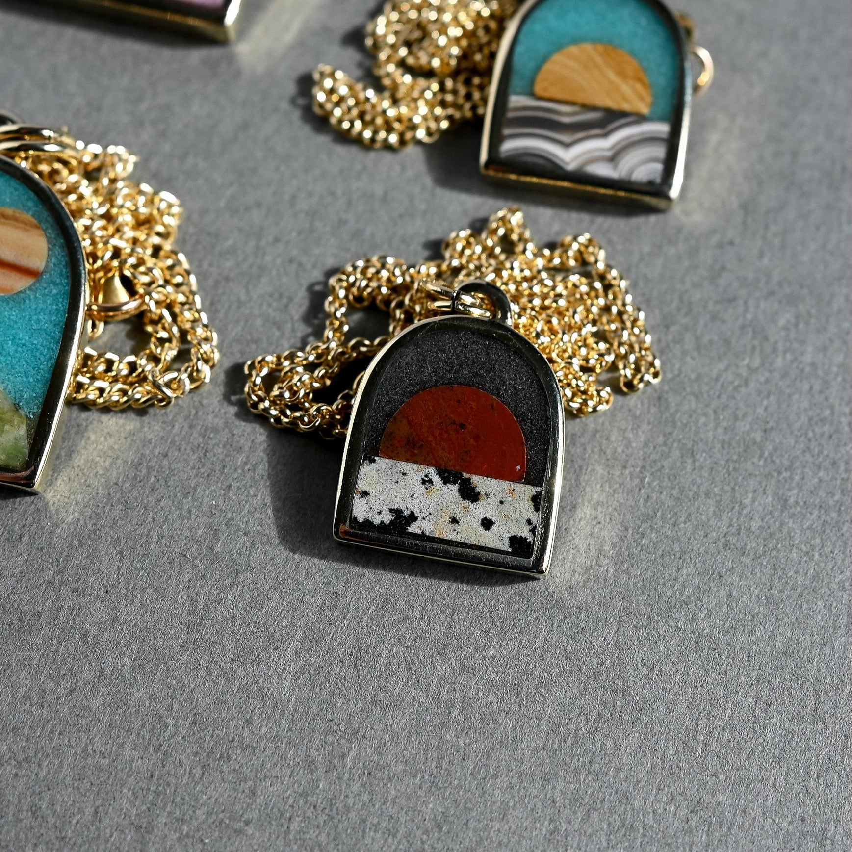 Set of necklaces with scenic pendants on a gray surface
