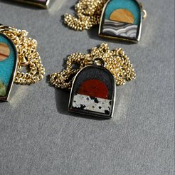 Set of necklaces with scenic pendants on a gray surface