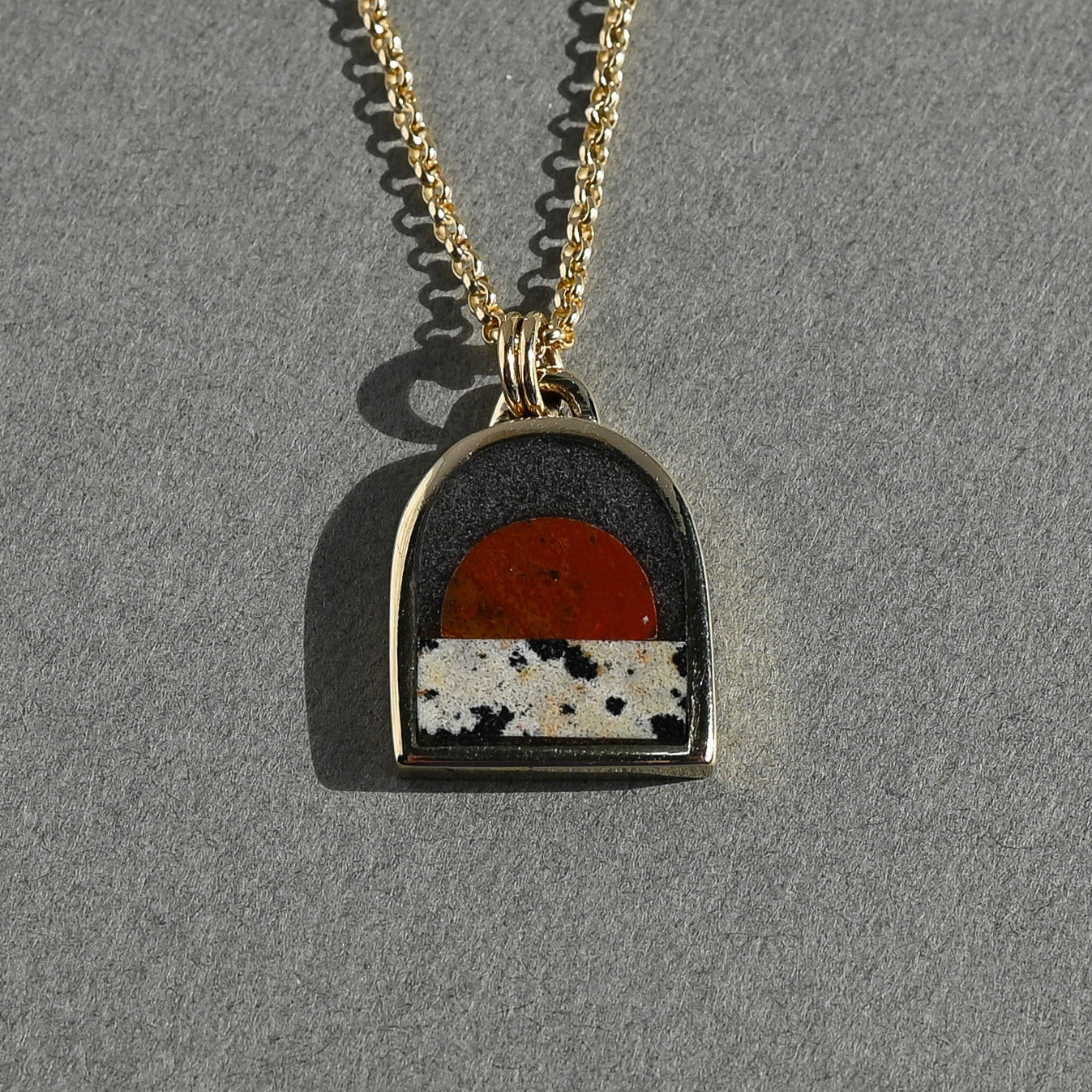 Necklace with a pendant featuring a sunset design on a gray background