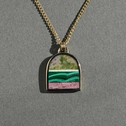 Necklace with a pendant featuring a green and pink stone on a gray background