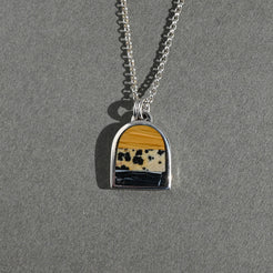 Necklace with a pendant featuring a yellow and black pattern on a gray background