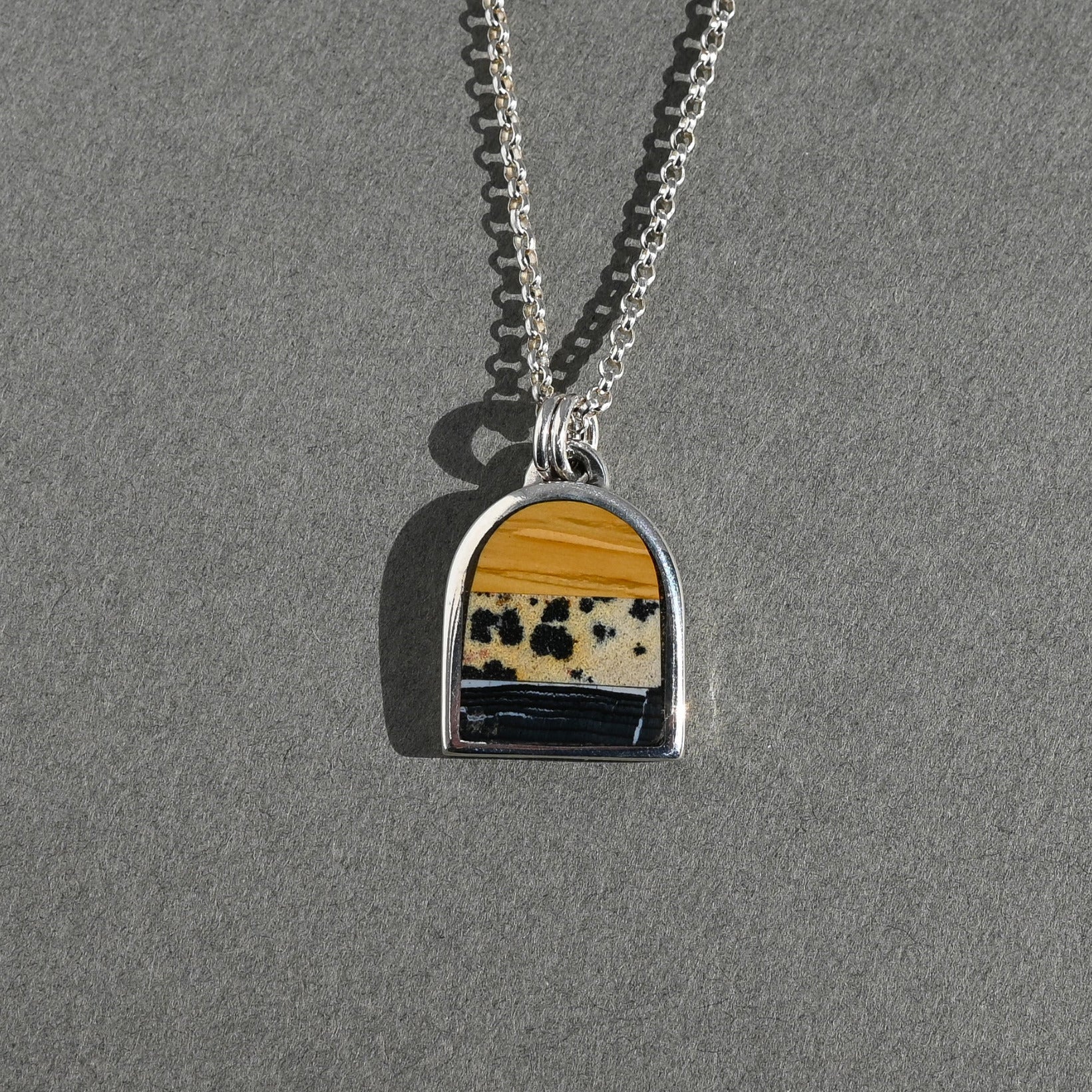 Necklace with a pendant featuring a yellow and black pattern on a gray background