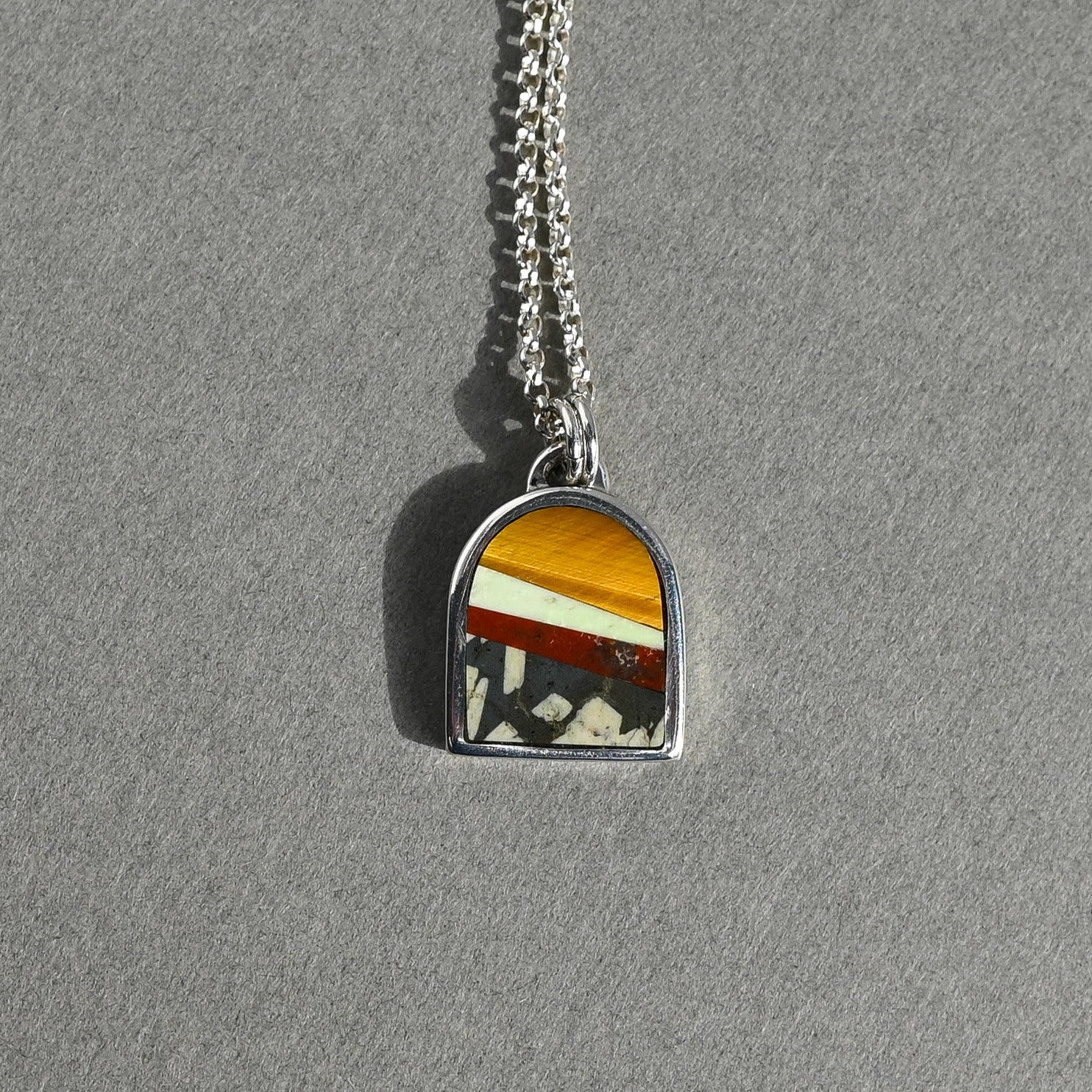 Necklace with a colorful stone pendant on a gray background