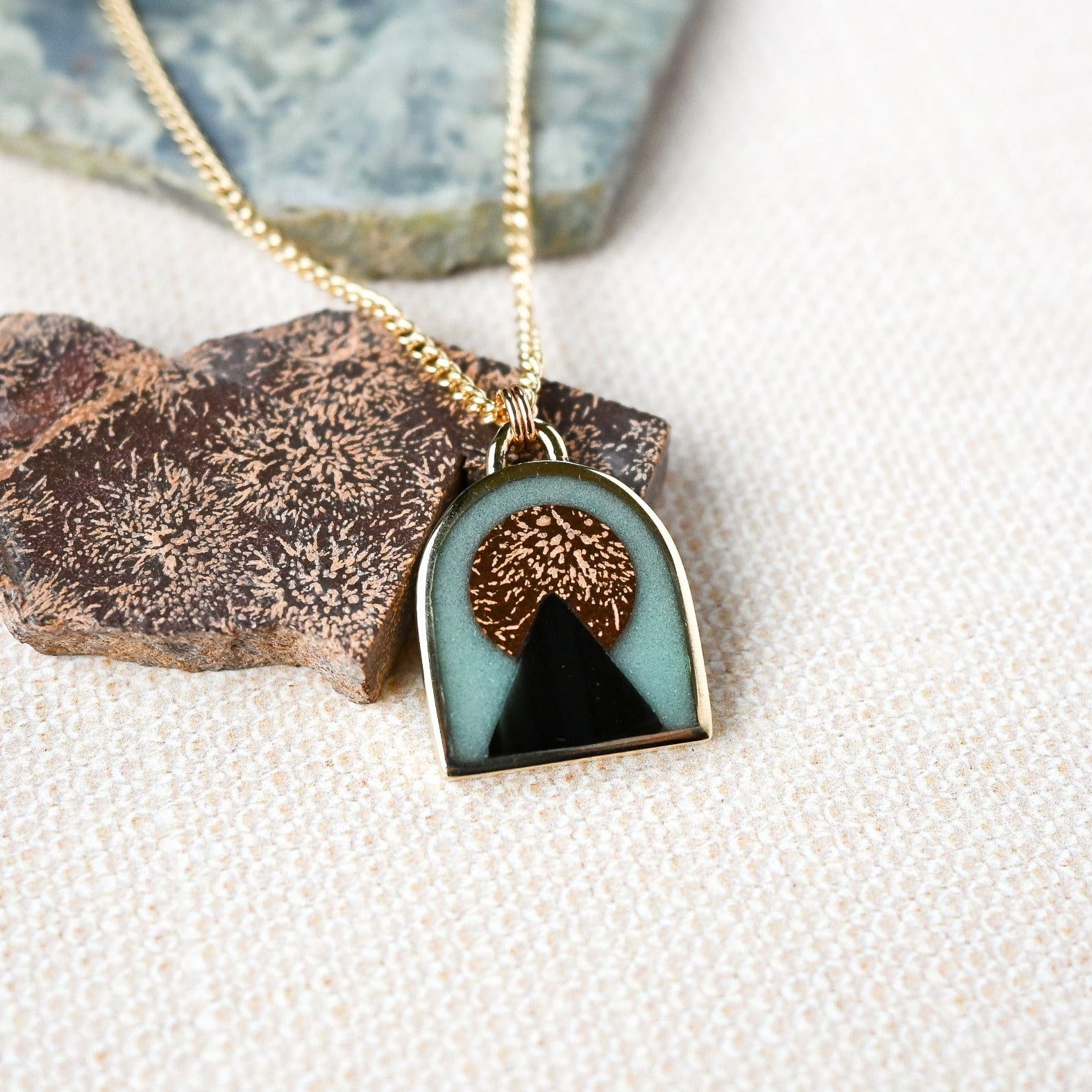 arch shaped gold pendant with temple image in stone