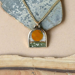 Necklace with a pendant featuring a sunset design on a textured surface