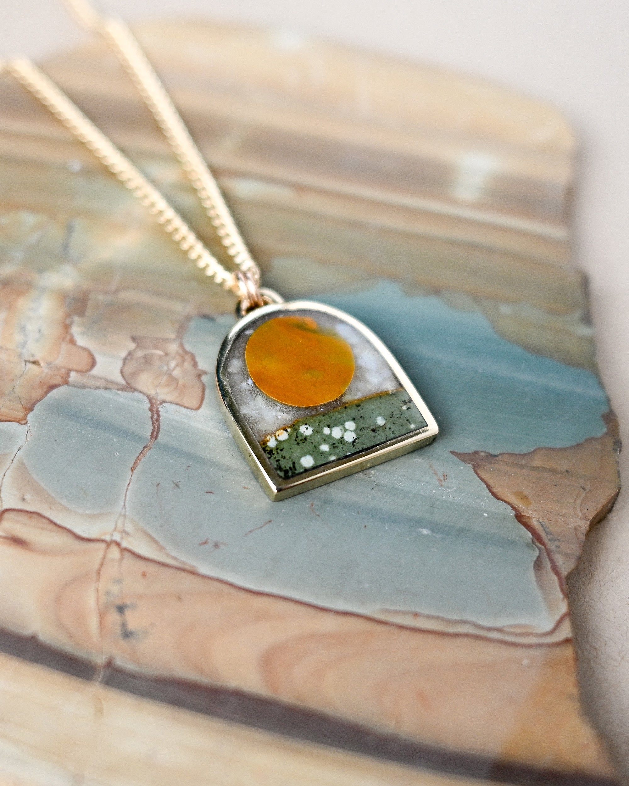 Necklace with a pendant featuring a yellow center and green accents on a textured surface.