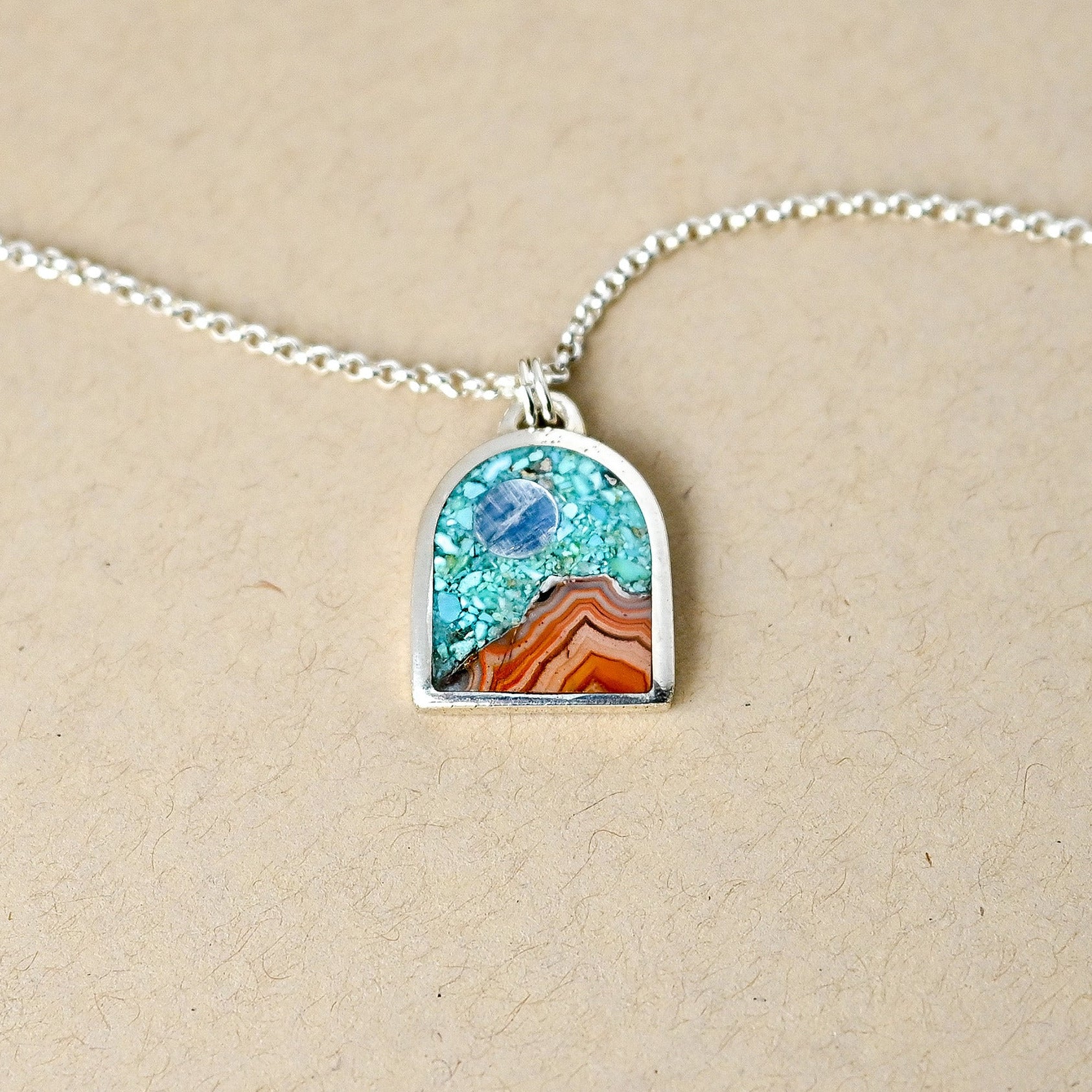 Necklace with a pendant featuring a scenic design on a beige background