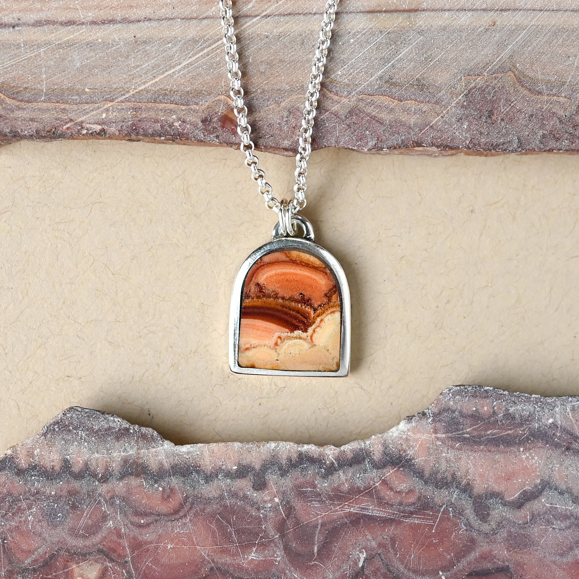 Sterling silver necklace with a wave dolomite pendant on a stone surface