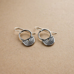 Pair of silver earrings on a beige background