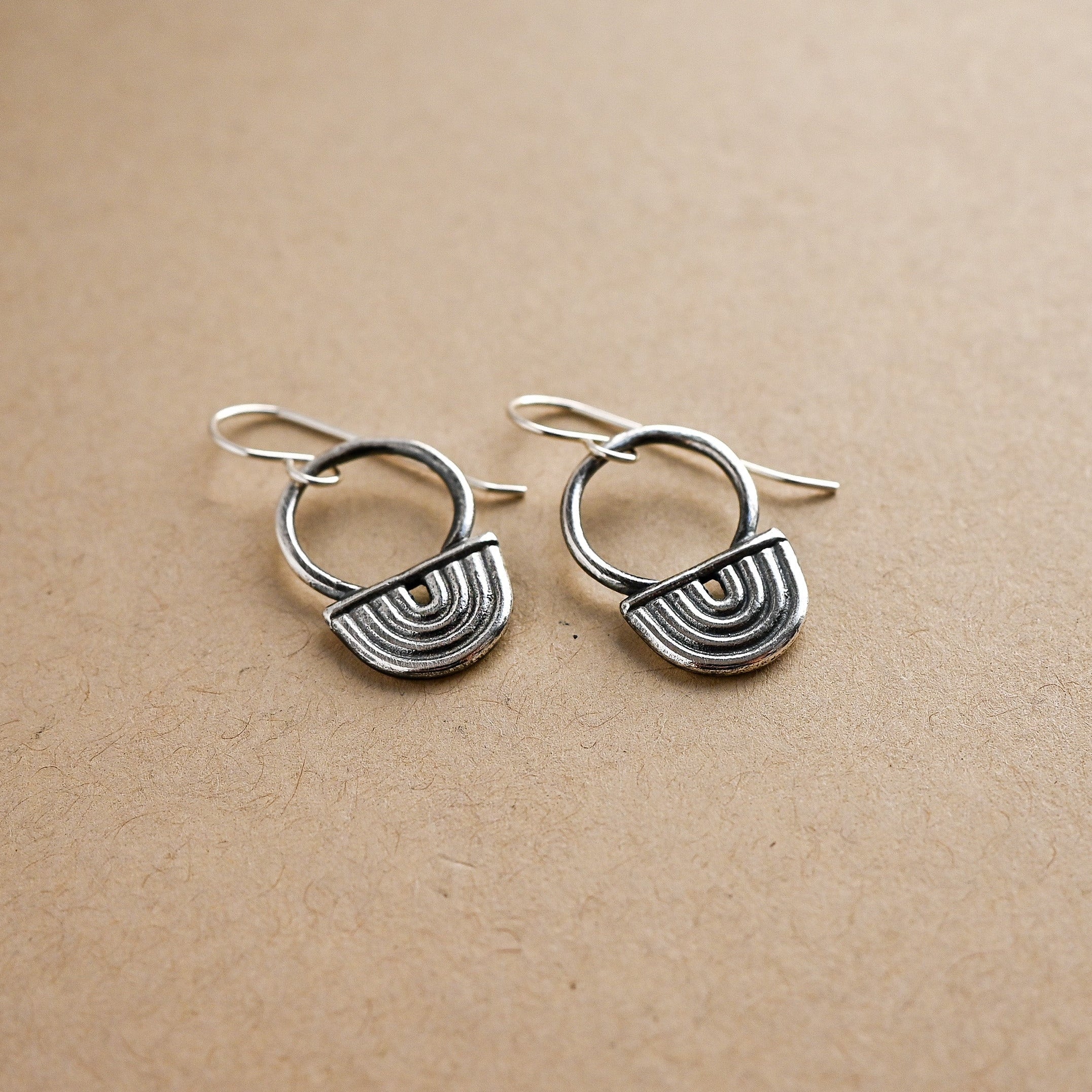 Pair of silver earrings on a beige background