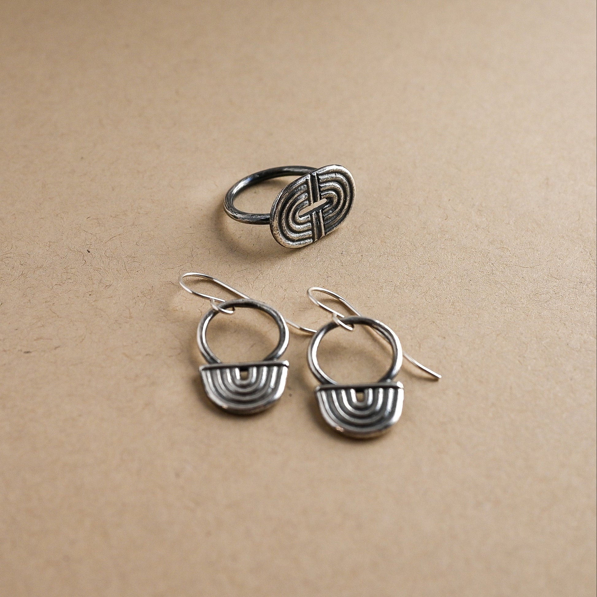Set of silver earrings and ring on a beige background