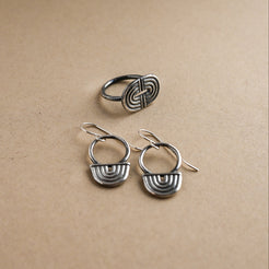 Set of silver earrings and ring on a beige background