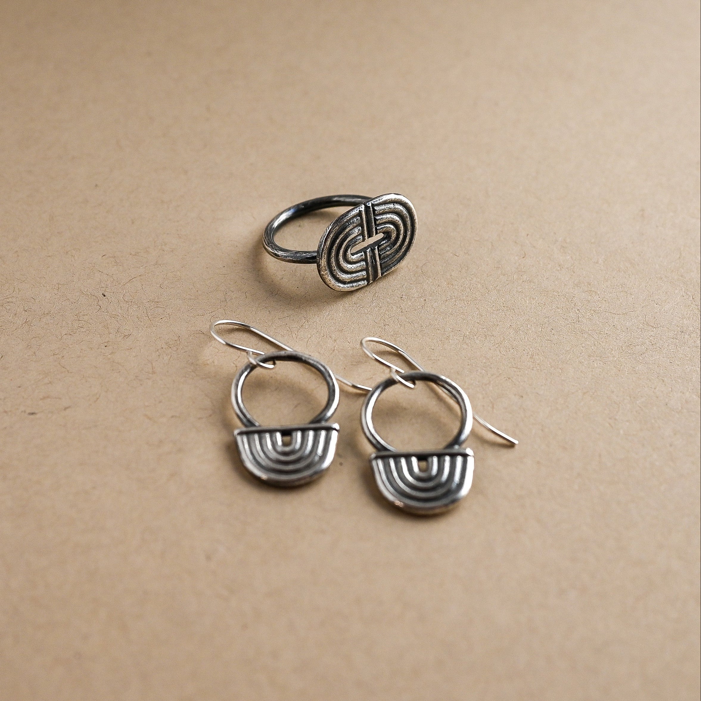 Set of silver earrings and ring on a beige background