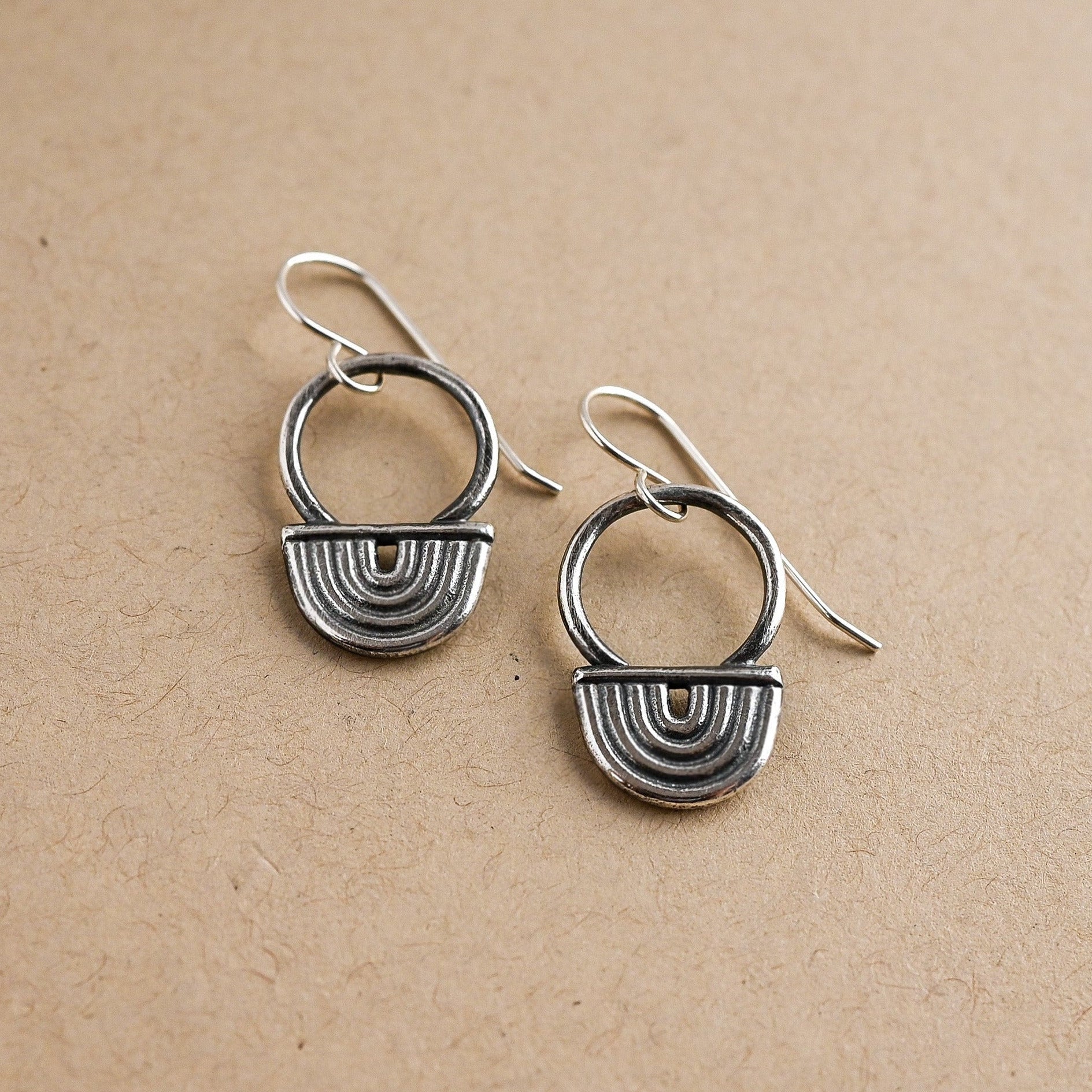 Pair of silver earrings on a beige background