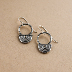 Pair of silver earrings on a beige background