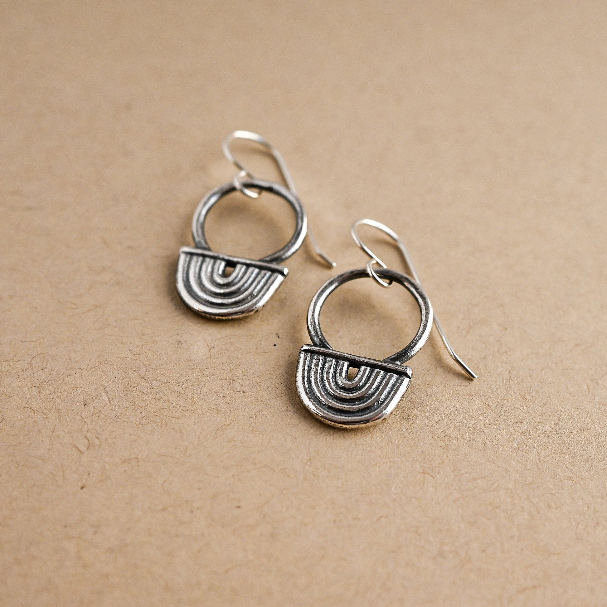 Pair of silver earrings on a beige background