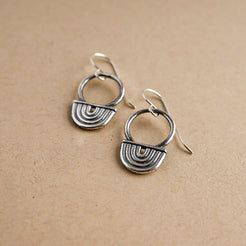Pair of silver earrings on a beige background