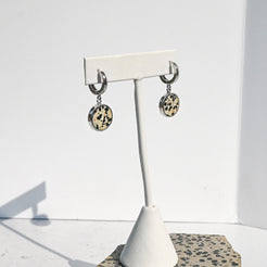Pair of earrings on a white stand with dalmatian stone pattern against a white background