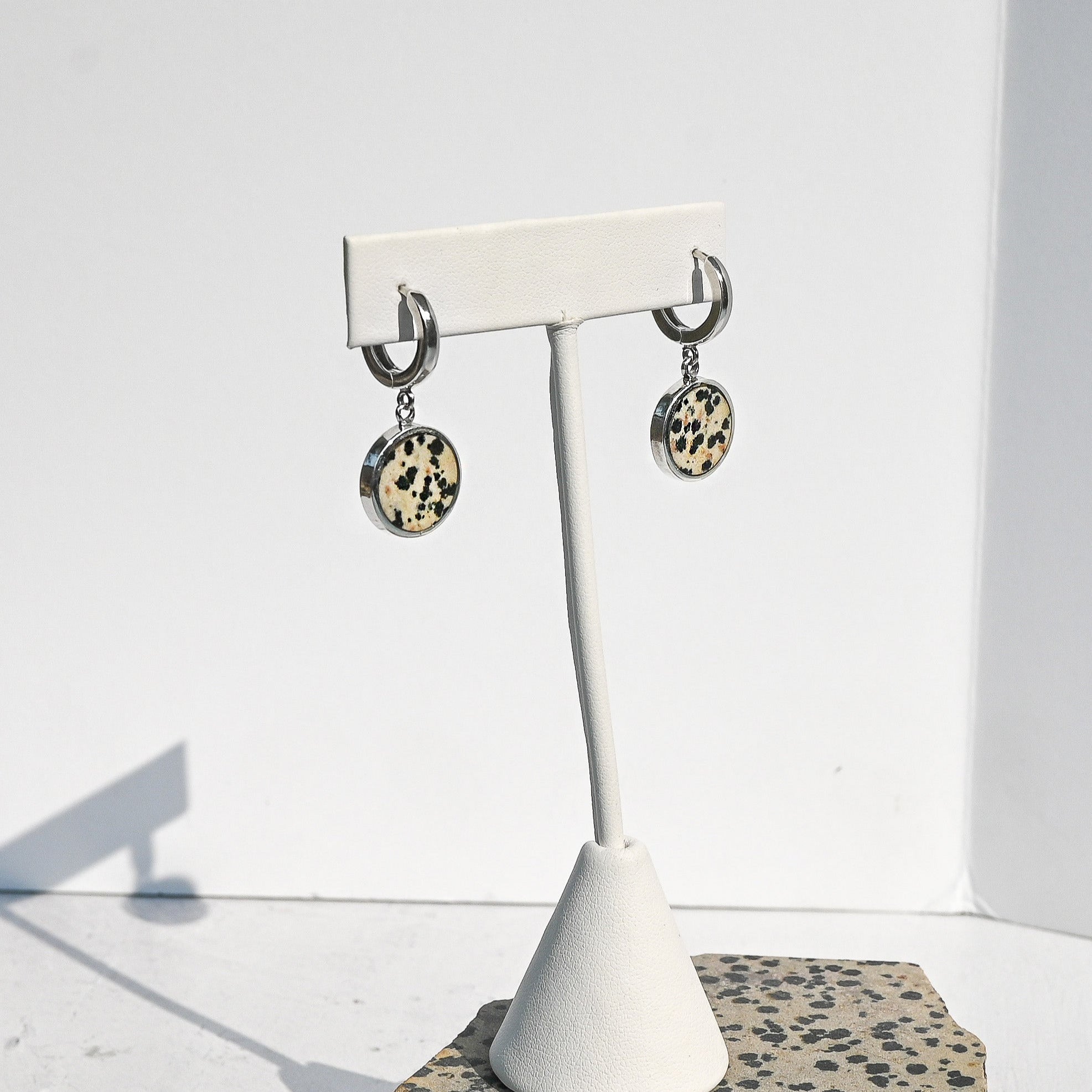 Pair of earrings on a white stand with dalmatian stone pattern against a white background