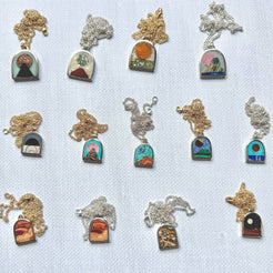 Collection of necklaces with scenic stone pendants on a light blue background