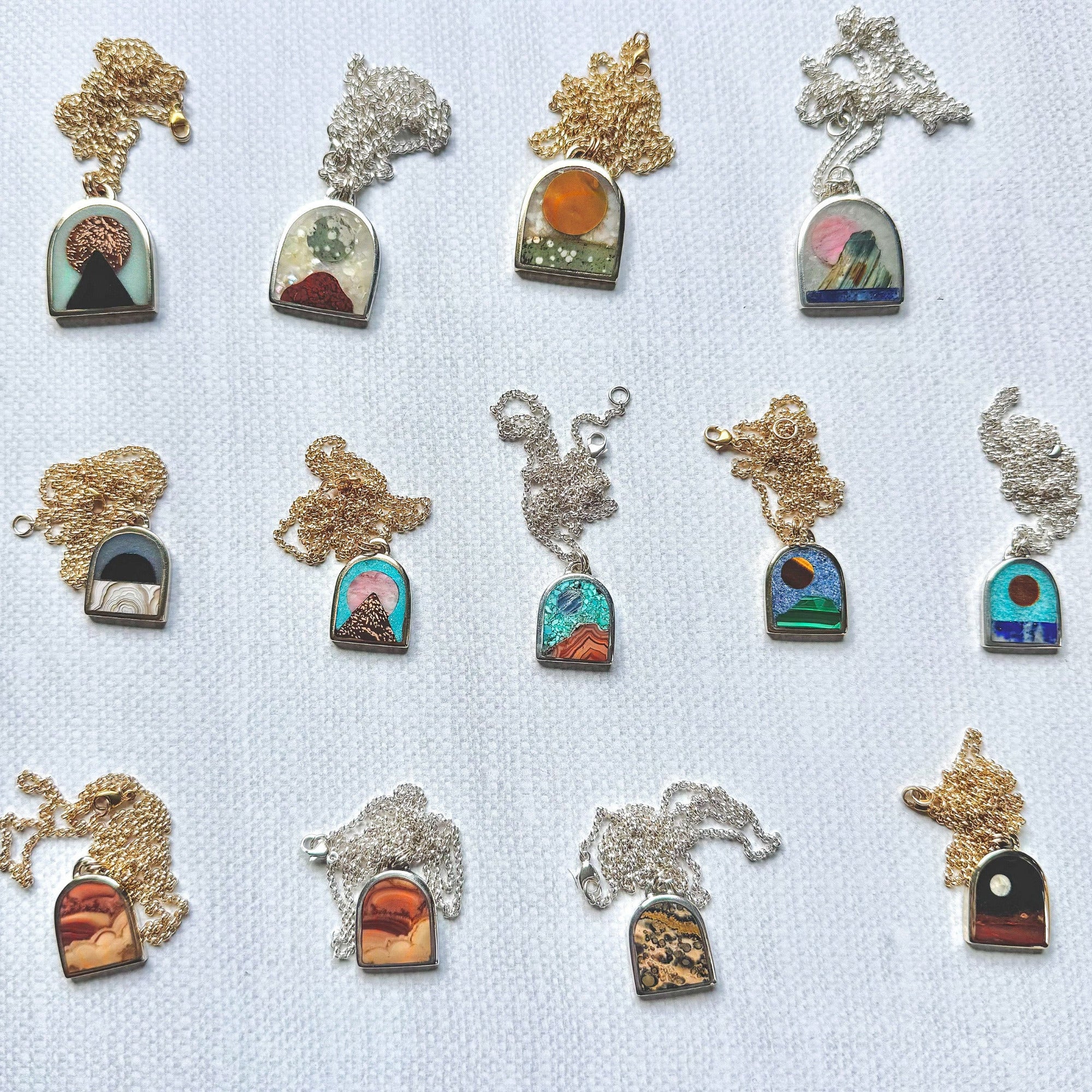 Collection of necklaces with scenic stone pendants on a light blue background