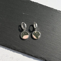 Silver hoop earrings with pink and black australian elephant stone charms on a dark slate surface
