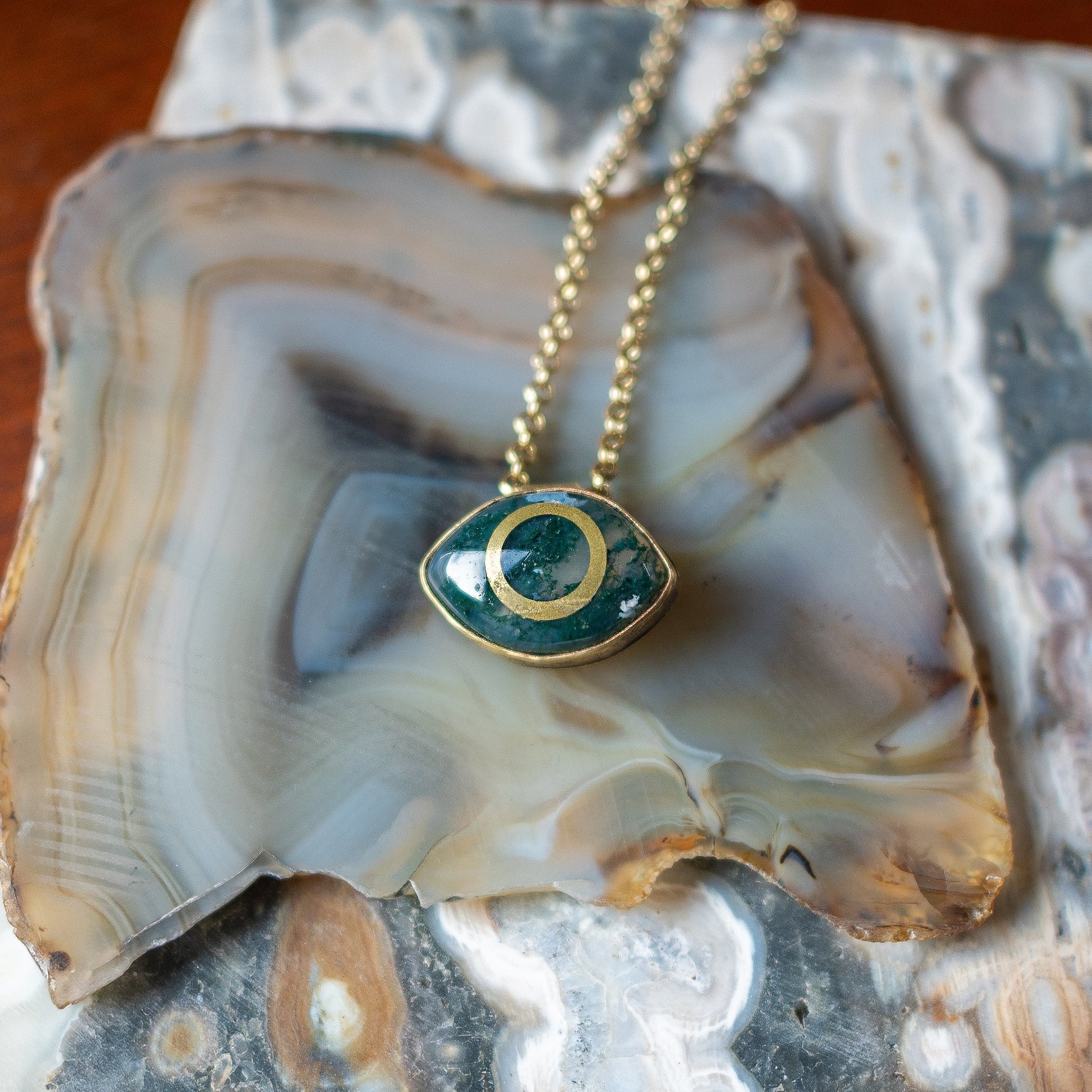 Necklace with a green moss agate eye pendant on a piece of agate stone