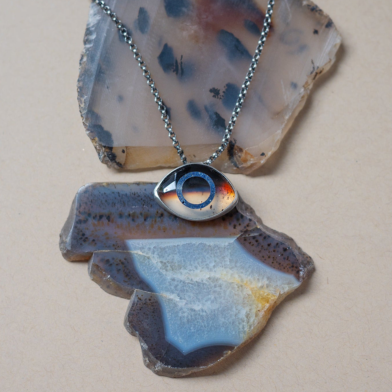 Necklace with a montana agate eye-shaped pendant on a stone surface