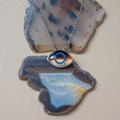 Necklace with a montana agate eye-shaped pendant on a stone surface