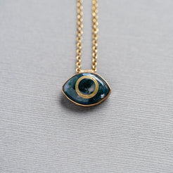 Necklace with a green moss agate eye-shaped stone pendant set in brass on a gray background