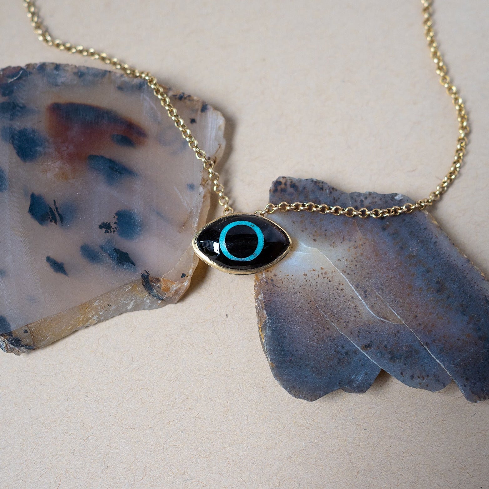 obsidian eye pendant with turquoise iris on an agate background