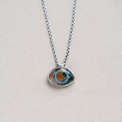 Necklace with a pendant featuring an ocean jasper eye shaped stone on a beige background