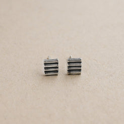 Pair of silver striped earrings on a beige background