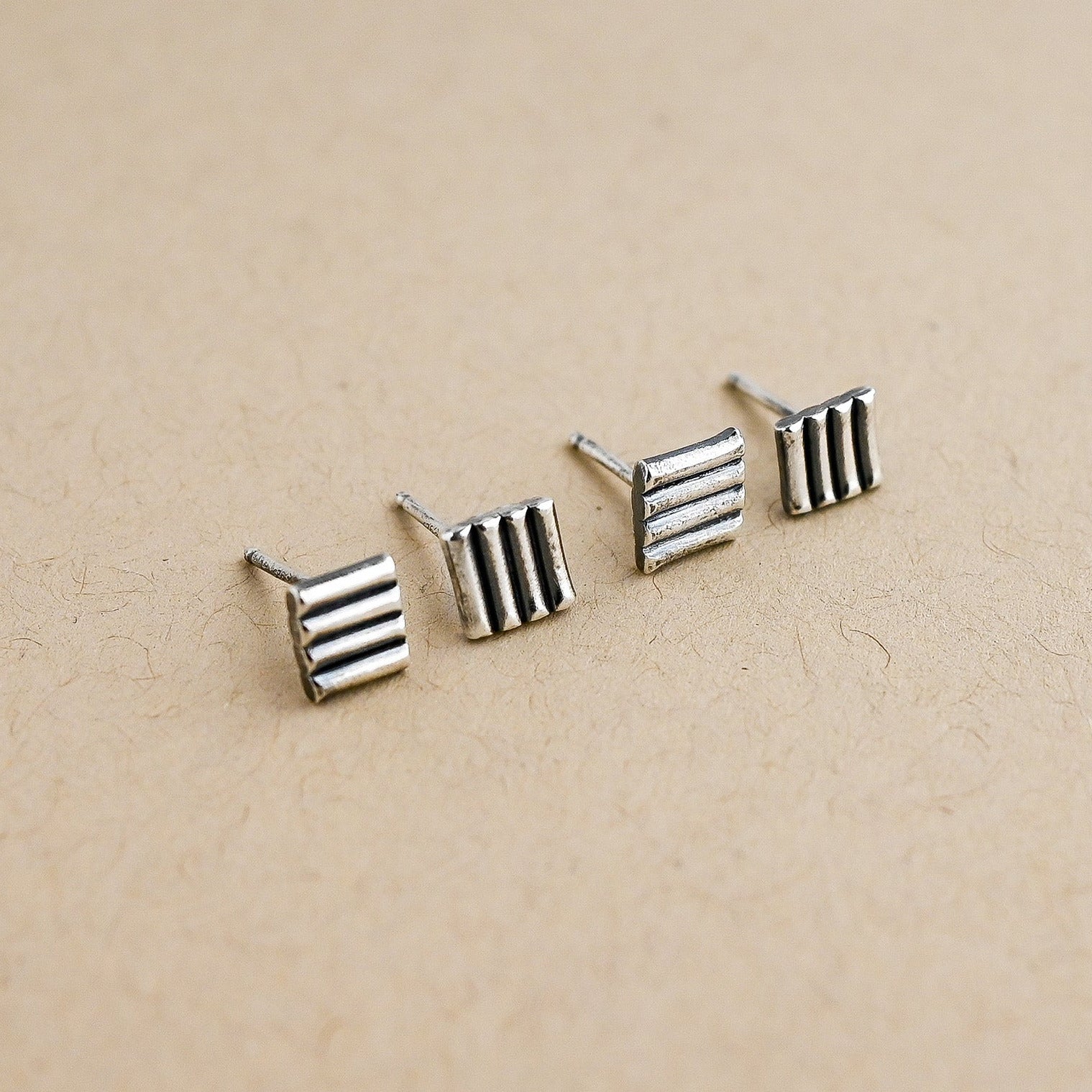 Set of silver striped earrings on a beige background