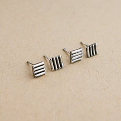 Set of silver striped earrings on a beige background