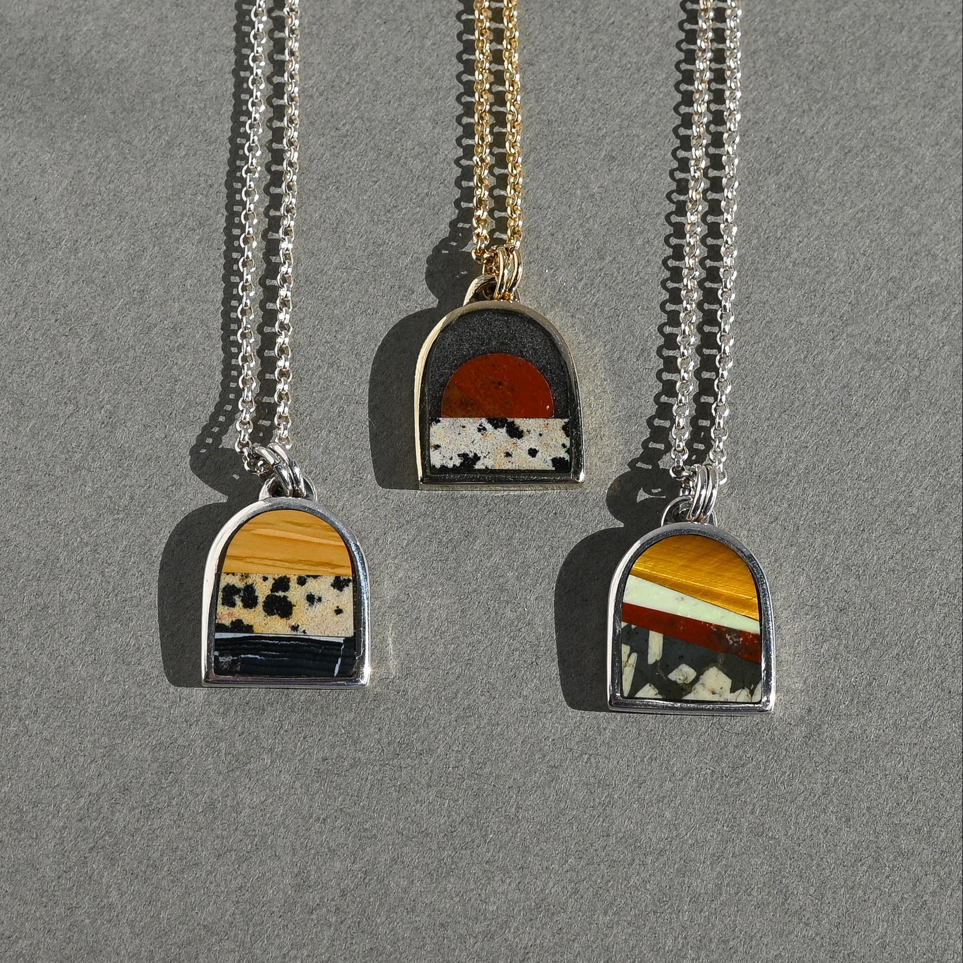 Three necklaces with unique pendants on a gray background