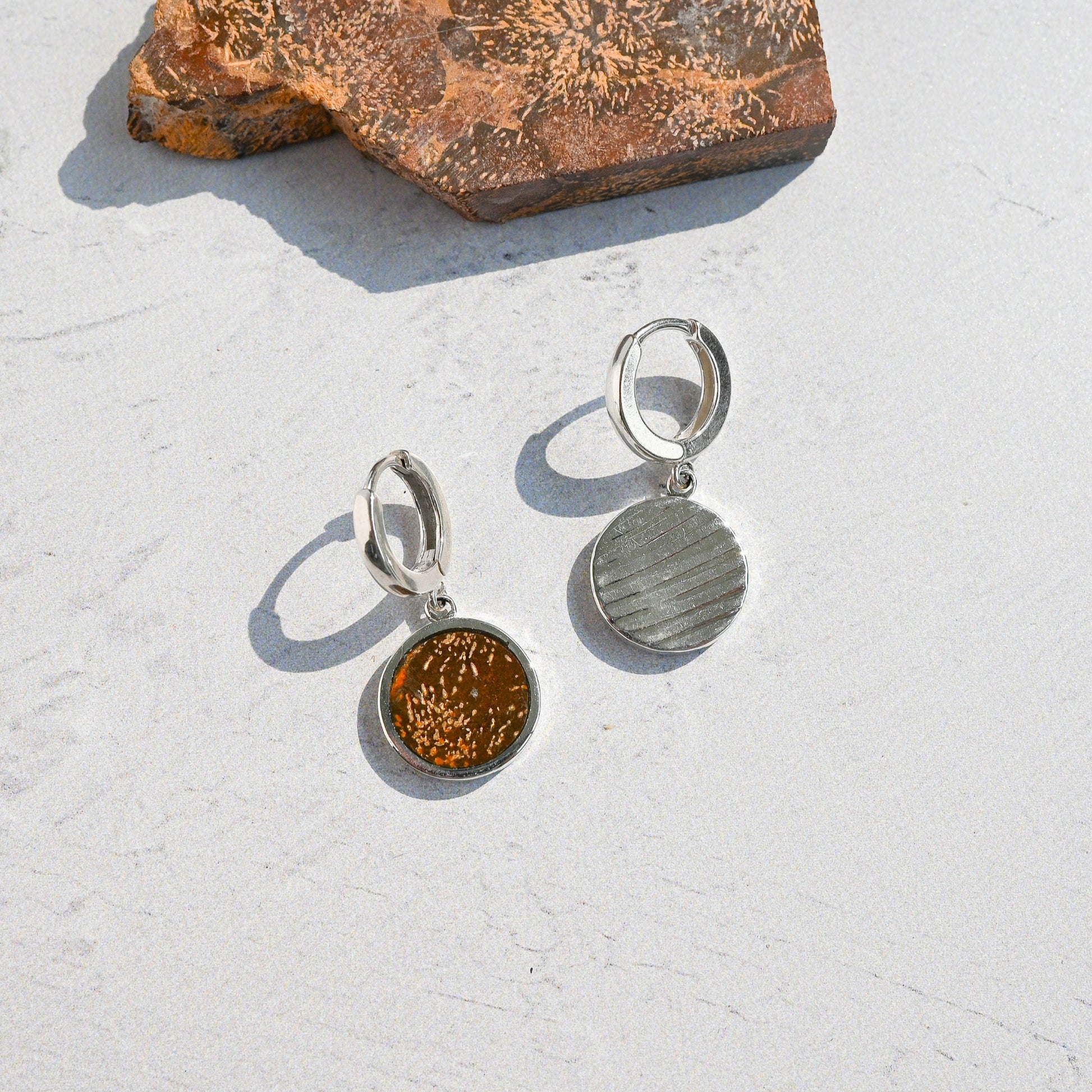 Pair of silver huggie hoop earrings with orange sunburst jasper charms