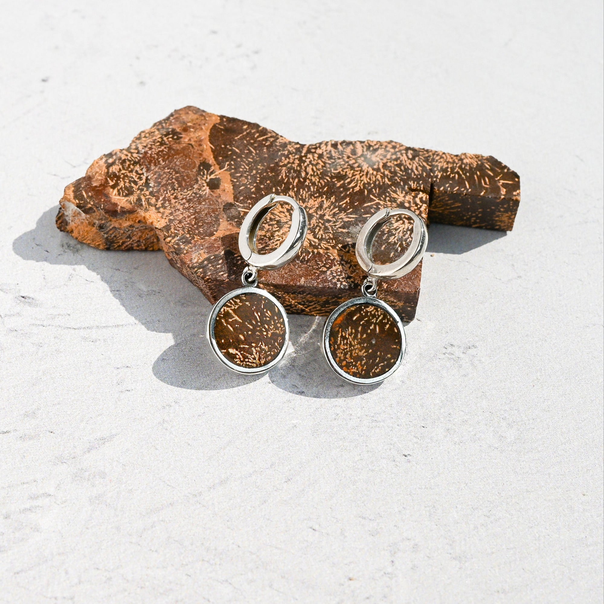 Pair of silver huggie hoop earrings with orange sunburst jasper charms