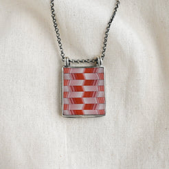 Necklace with a red and white checkered pendant on a beige fabric background