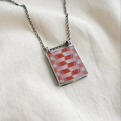 Necklace with a geometric pendant on a white fabric background