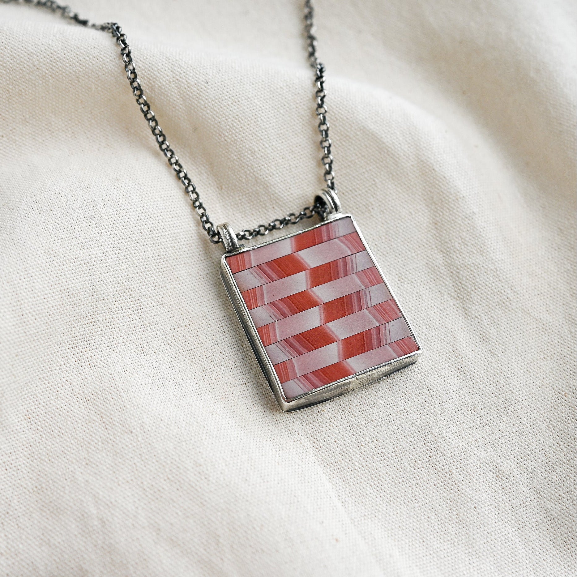 Necklace with a geometric pendant on a white fabric background