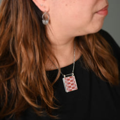 Close-up of a woman wearing a necklace with a checkered pendant.