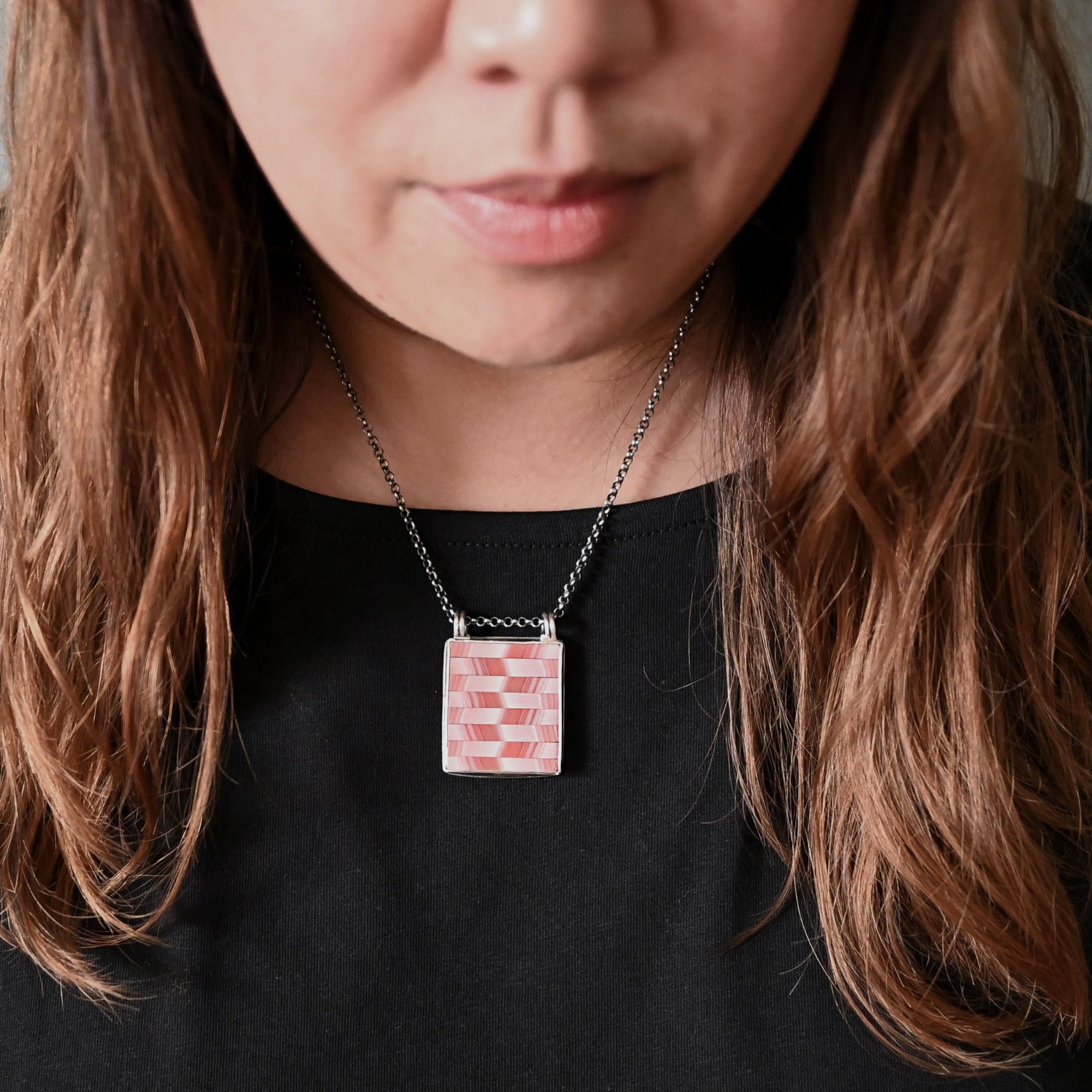 Person wearing a necklace with a checkered pendant