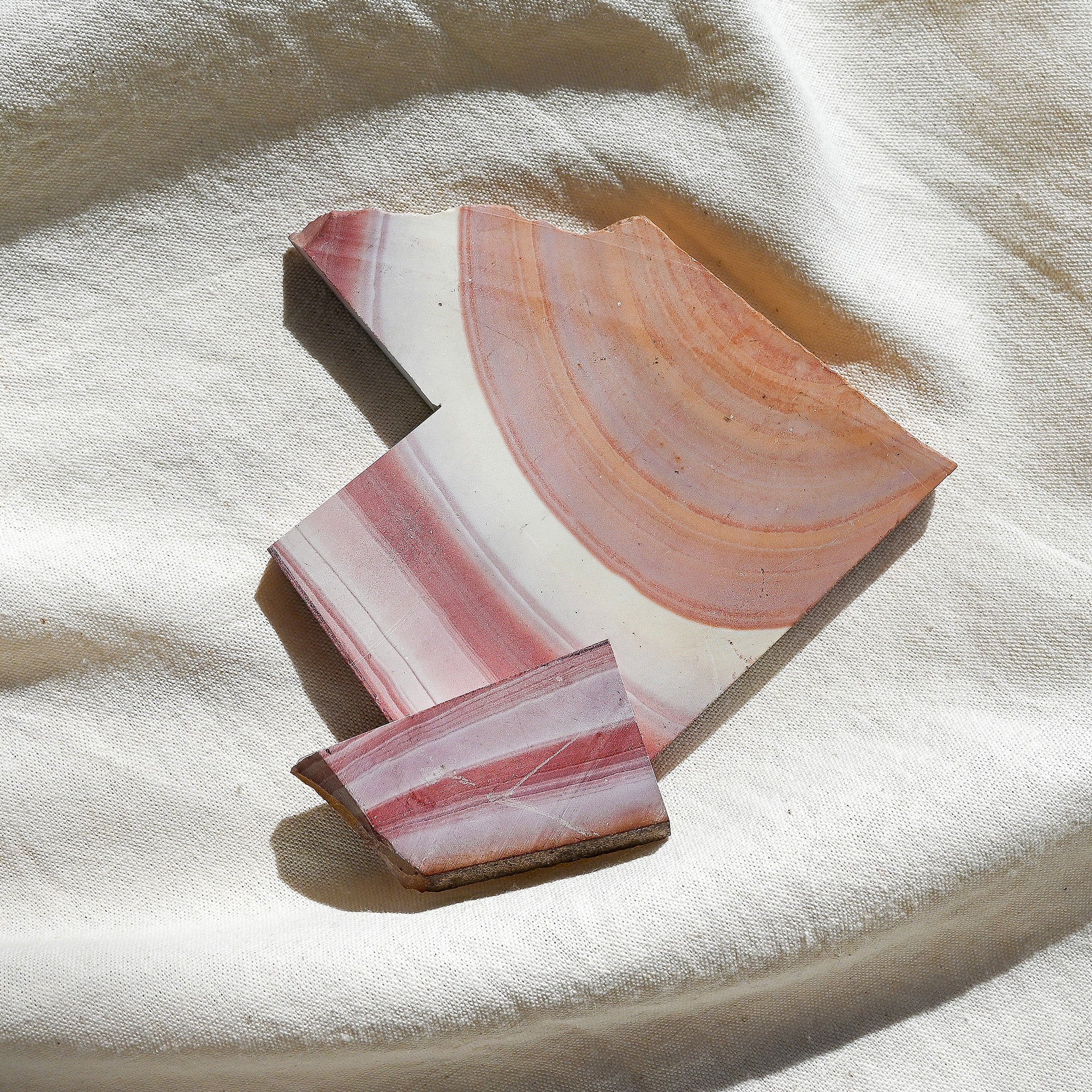Polished pink and white stone on a textured beige surface